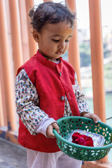 isolated cute kid devotee with holy offerings at temple in indian traditional dress