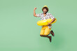 © ViDi Studio - Full body young happy excited overjoyed Indian man wear beach shirt hat rest near hotel pool jump high do winner gesture isolated on plain green color background. Summer vacation sea sun tan concept.