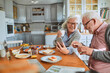 © Marko Geber - Happy senior couple eating breakfast together at kitchen table