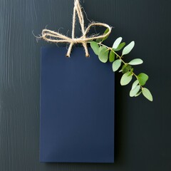 Wall Mural - Blank tag with string and leaves, arranged on a dark background.