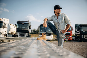 Foot is on the trailer. Truck driver is near the transport outdoors