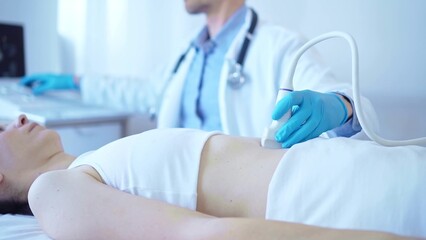 Wall Mural - Doctor man wearing a blue medical gloves using an ultrasound equipment on a female patient lying down in clinic cabinet. Medicine concept