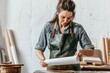 © Fotograf - A woman wearing an apron is seated at a desk, focusing on a piece of paper
