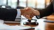 © Maksym - A legal consultation ends with a handshake between a lawyer and her client, framed by an office filled with law books, a wooden gavel, and neatly stacked legal documents on the des