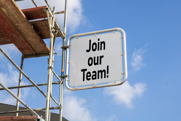 House with scaffolding with blue sky background with big sign and german letters for join our team - komm in unser team