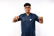© ArvStd - Healthcare workers concept. Happy smiling handsome asian nurse, male doctor in scrubs pointing down, inviting for checkup, showing hospital advertisement, white background