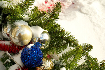 An outside Christmas tree branches s decorated with bright balls made of glass. The branches are covered with frost. New Year background. Decorative gifts for Christmas.