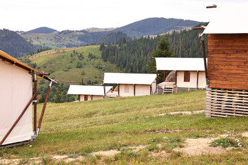 Poster - Green forest and many houses in mountains. Glamping site