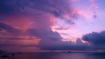 Wall Mural - Cloudscape view time lapse horizon over ocean ships boats, islands and mountains visible in distance with purple pink orange cumulonimbus clouds before sunrise early in the morning