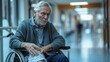 © เลิศลักษณ์ ทิพชัย - A senior man is seen in a wheelchair, clutching his hurting knee and displaying a brief moment of discomfort. The background shows a hospital hallway.