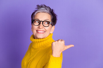 Sticker - Photo of adorable funny woman yellow knitwear looking pointing thumb back empty space isolated violet color background