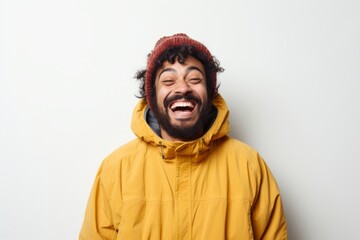 Wall Mural - Portrait of a cheerful indian man in his 30s wearing a warm parka isolated on white background