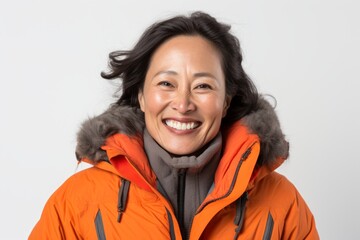 Wall Mural - Portrait of a grinning asian woman in her 50s donning a durable down jacket while standing against white background