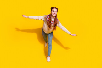 Wall Mural - Photo portrait of attractive young woman spread hands flying dressed stylish knitted warm outfit isolated on yellow color background