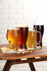 Poster - Glasses with different types of beer and snacks on wooden table