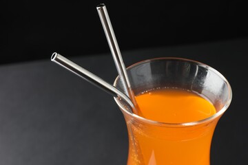 Tasty refreshing drink with straws in glass on dark background, closeup