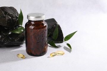 Wall Mural - Medical bottle with pills, green leaves and stones on white textured table, space for text