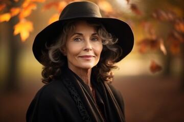 Sticker - Portrait of a tender woman in her 60s donning a classic fedora on background of autumn leaves