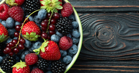 Poster - Mix of ripe colorful berries in bowl photography . Blueberry , strawberry , raspberry , blackberry and red currant . Top view