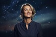 © Markus Schröder - Portrait of a happy woman in her 40s donning a classy polo shirt while standing against backdrop of starlit galaxies