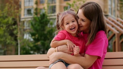 a child and his mother are talking on a park bench in the summer, having fun together, a happy child