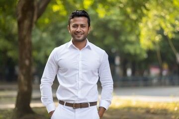 Wall Mural - Portrait of a blissful indian man in his 30s wearing a classic white shirt isolated on vibrant city park