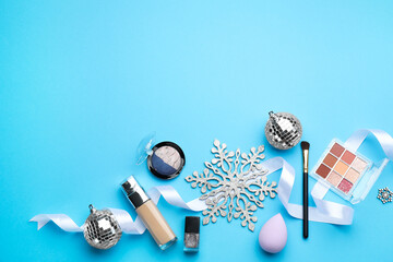 Poster - Flat lay composition with makeup products and Christmas decor on light blue background. Space for text