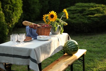 Wall Mural - Glasses, plates, fresh products and sunflowers on table in garden