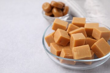 Poster - Tasty sweet caramel candies on light grey table, closeup. Space for text