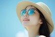 © Fotograf - A woman wearing a straw hat and sunglasses, casual outdoor look