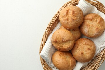 Wall Mural - Wicker basket with homemade tasty buns on white table, top view. Space for text