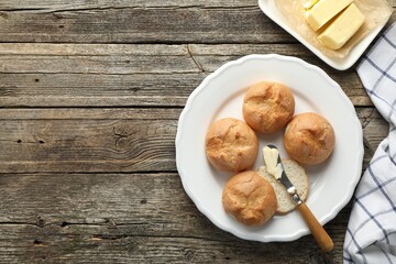 Wall Mural - Plate with homemade tasty buns, butter and knife on wooden table, flat lay. Space for text