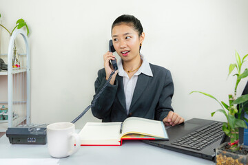 Young Business Manager Female Office Receptionist with Phone and Notepad Gives gestures Working in Laptop Customer Service Doing paperwork