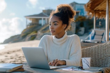 Poster - A woman sits at a table with a laptop open, focused on her work