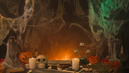 Dark spooky kitchen in spider webs, with sinister pumpkins the table, frightening human skull and bones, as well Ouija board.