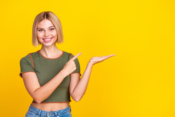 Poster - Photo of nice cute girl with bob hair dressed khaki t-shirt directing at object on palm empty space isolated on yellow color background