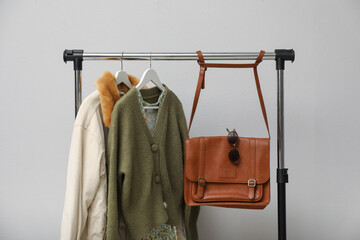 Canvas Print - Rack with clothes and bag near light wall