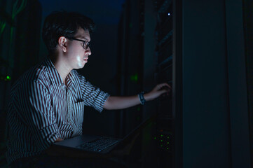 Computer engineer is setting up network in server room,Systems Maintenance Technician,Male engineer working in server room at modern data center