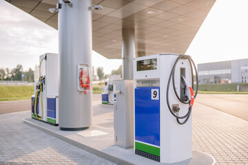  A modern gas station with fuel pumps and a fire extinguisher on the pillar, featuring a clean, spacious layout and contemporary design.