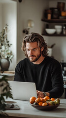Poster - A man is sitting at a table with a laptop and a bowl of fruit