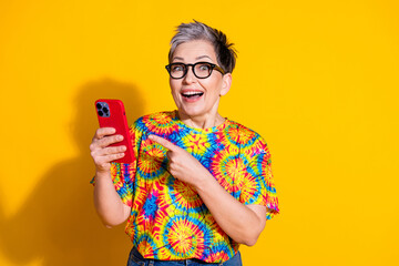 Canvas Print - Photo of nice aged lady indicate finger smart phone wear t-shirt isolated on yellow color background