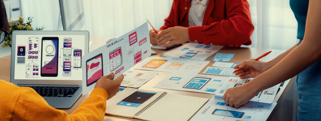 Panorama banner of startup UX developer or company employee design user interface or UI prototype for mobile application or website software with software display on laptop monitor in office. Synergic