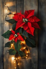 Vibrant red poinsettia flower against rustic wooden backdrop adorned with twinkling lights