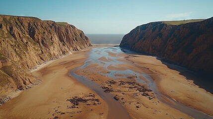 Poster -   A bird's eye view of a winding river traversing a sandy shore alongside towering cliffs and tranquil waters