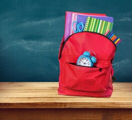 Sticker - school backpack with stationery on table near chalkboard