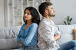 © Home-stock - Indian couple sitting back to back on couch at home, upset spouses offended after quarrel, suffering problems in relationship