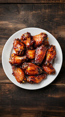 Delicious barbecue chicken wings on a white plate, rustic wooden table. Succulent grilled meat in flavorful sauce, perfect meal or snack. Showcasing american cuisine