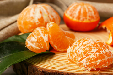 Wooden board with tasty tangerines and leaves, closeup