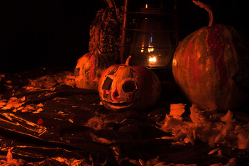 art scary Halloween with pumpkins and an old kerosene lamp in a red light preparation for the celebration in a dark room 