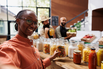 Canvas Print - African american woman compliments an undiscovered eco-friendly local supermarket in her vlog, showcasing excellent organic products. Female influencer presenting a new sustainable bio store.